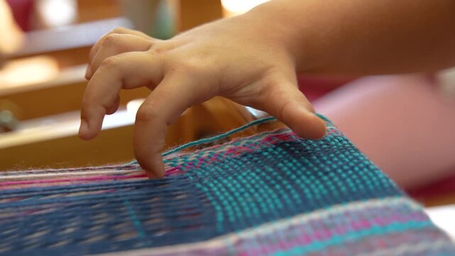 Slow motion close up of hand weaving colorful textile on traditional loom