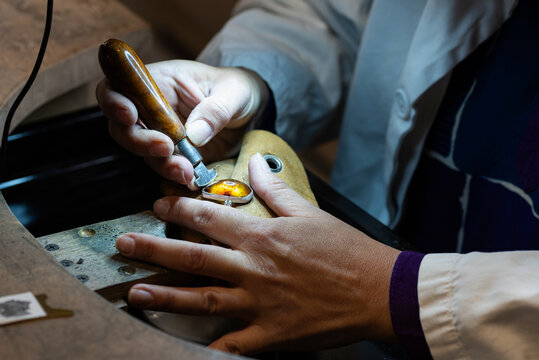 A female stonesetter fixing an amber stone into a silver ring.
