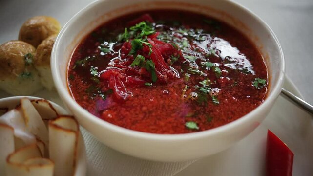 Top down view of a bowl of traditional beetroot soup, garnished with chopped parsley and sour cream