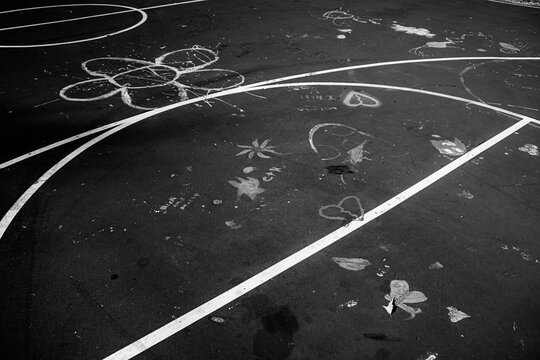     Black and white basketball court with chalk drawings on pavement, urban street playground with empty blacktop and minimal grunge texture
