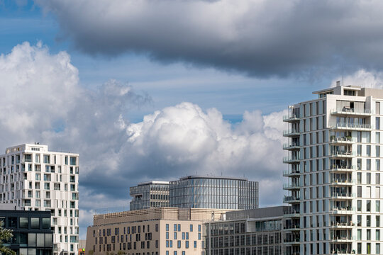 Under dramatic clouds, an urban skyline gathers apartments and buildings into layered architecture, with sky, towers, weather and daylight around residential blocks.