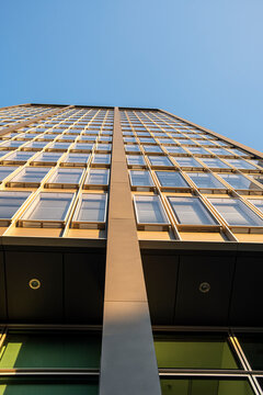 Seen from below, a building facade turns urban architecture into a measured climb of windows and vertical geometry, with perspective leading into clear sky.