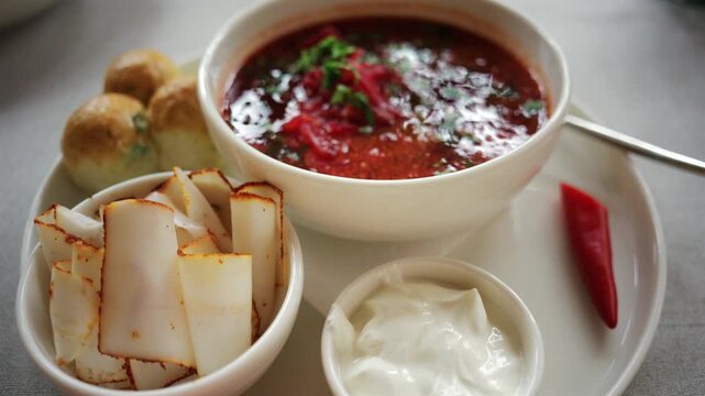 Top down view of a bowl of traditional beetroot soup, garnished with chopped parsley and sour cream