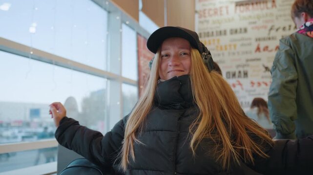 Relaxed traveler enjoying layover. Casual scene with woman at airport. Portrait of woman smiling during airport stopover. Informal snapshot of woman resting at airport terminal with joyful expression
