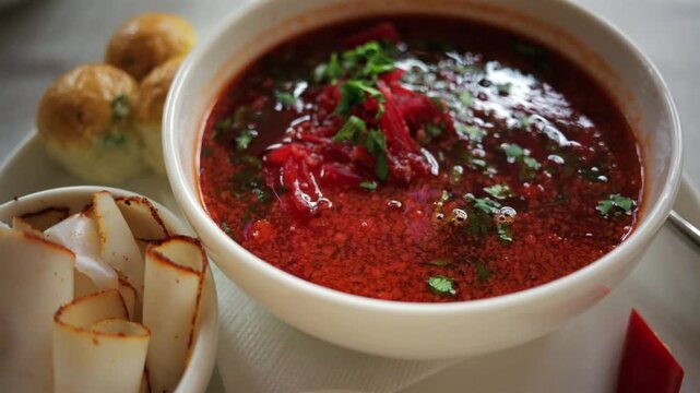 Top down view of a bowl of traditional beetroot soup, garnished with chopped parsley and sour cream
