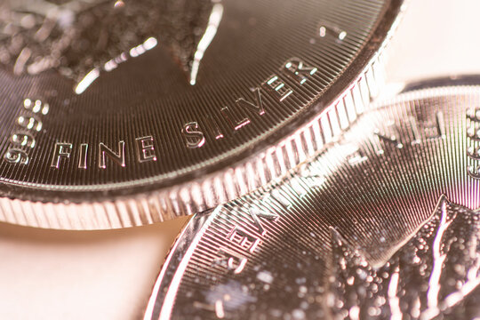 A fine silver coin resting on another silver coin, representing silver prices and critical metals.