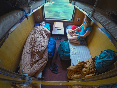 Male and female backpackers resting while travelling in a cool sleeper train.