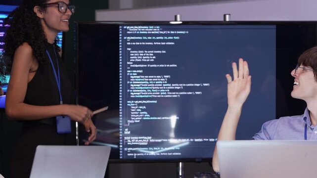 Two professional software developers collaborating on system logic design and flowchart analysis on a tablet screen in a modern office.