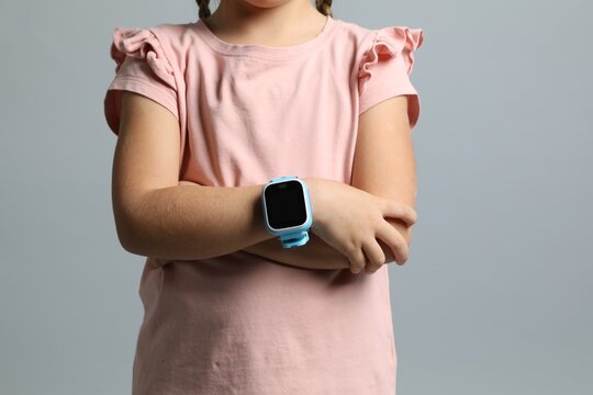 Little girl with smart watch on grey background, closeup
