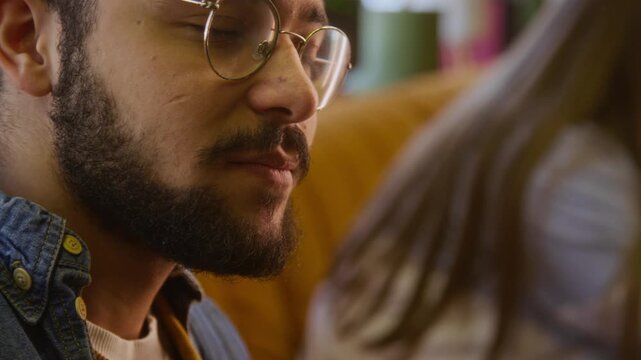 Close up shot of biracial bearded man in glasses enjoying crisp french fries with ketchup in modern fast food cafe
