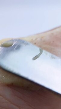 Close up process of spreading natural moisturizing cream on skin using metal applicator. Detailed cream texture, smooth spreading motion, and organic skincare routine. Beauty and wellness concept.