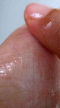 Applying moisturizing liquid evenly onto hand skin. Close up view with shiny oily finish, hydration concept for healthy glowing skin