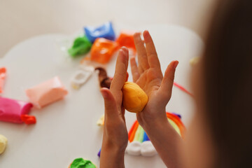 Hands skillfully mold vibrant yellow play dough while surrounded by an array of other colors. This artistic moment captures creativity in a cheerful setting © sementsova321