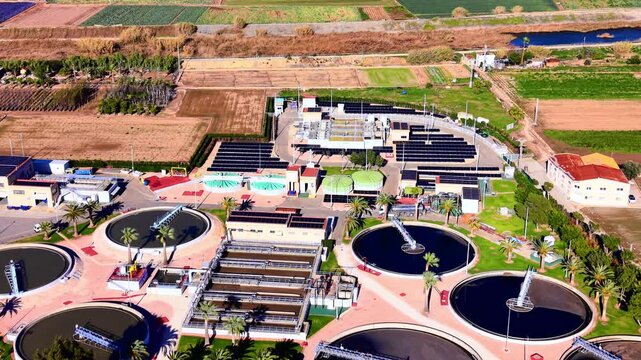 Aerial view of industrial clarifier tanks and rows of photovoltaic panels at a sustainable treatment facility. Modern water purification system with solar panel arrays