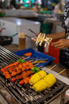 bustling night market in Bangkok, colorful street food stalls serving sizzling skewers, people enjoying authentic Thai cuisine