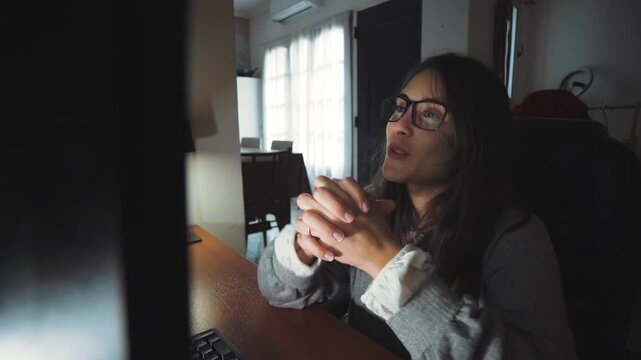 Video of a young woman making a work video call from home. Hybrid work, remote communication, and professional lifestyle concept.
