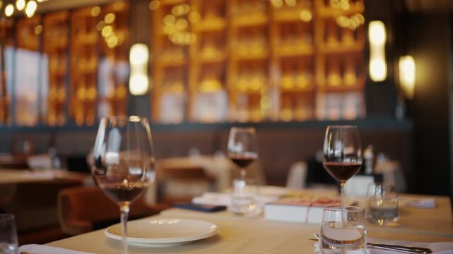 Elegant restaurant table setup with multiple wine glasses, plates, and warm ambient lighting