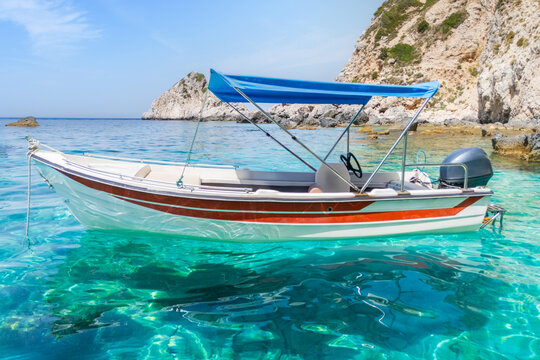 Aerial view on clear turquoise blue water with empty white speed boat on small Kastelli beach on Corfu island. High speed boat trip on Ionian sea.