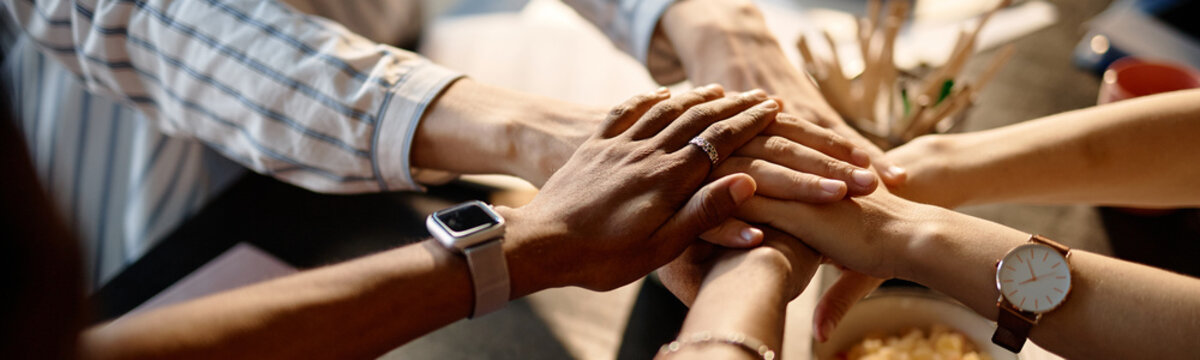Website header shot of diverse business team joining hands in workplace, symbolizing teamwork, trust, collaboration, close up view. Ideal for corporate culture, leadership, partnership marketing