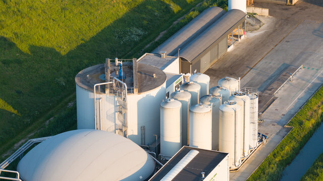 Aerial view of the Wabico BV biogas plant featuring large storage silos and a white dome structure next to a green embankment Waalwijk, Noord-Brabant, Netherlands.