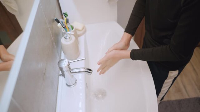 Child cleaning hands diligently. Boy carefully scrubs his hands with soap in bright bathroom. Young boy methodically washing and rinsing his hands using soap in luminous bathroom setting