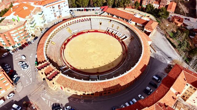 Aerial perspective of a traditional spanish bullfighting arena with red wooden barriers. Top view of empty bullring arena with tiered seating.