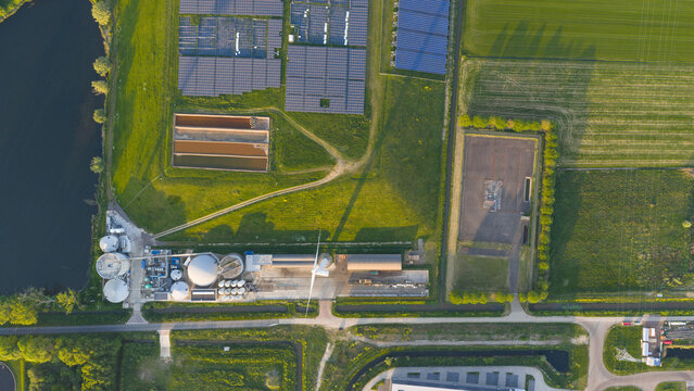 Aerial view of Wabico BV biogas plant featuring solar panel arrays, industrial tanks, and green fields under golden hour light in Waalwijk, Noord-Brabant, Netherlands.