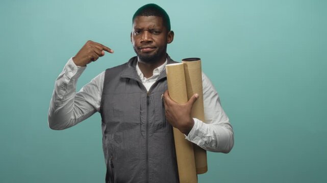 Man holding rolled blueprints, pointing finger to his head and gripping plans as architect in studio; confidence planning design.