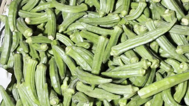 Large pile of fresh green okra vegetables at a local market for healthy cooking background