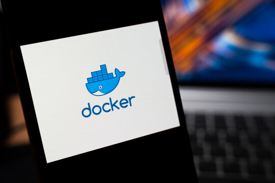 Warsaw, Poland - May 13, 2026: Docker logo displayed on smartphone screen with blurred laptop in background, representing technology and software development.
