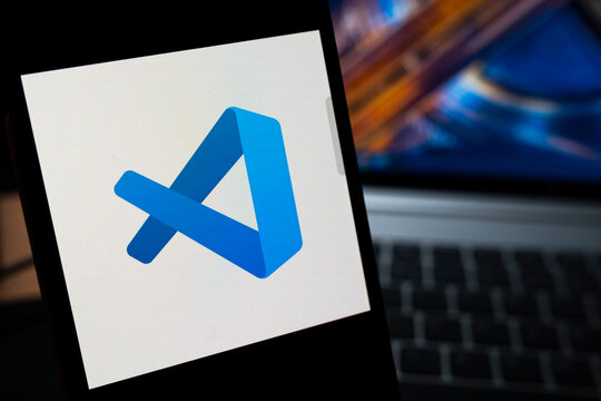 Warsaw, Poland - May 13, 2026: An abstract representation of the Visual Studio Code logo displayed on a smartphone screen, illustrating the concept of modern coding and software development.