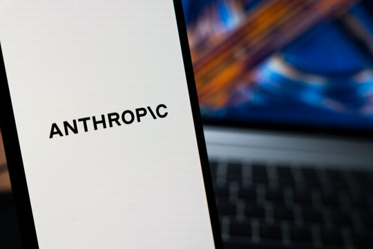 Warsaw, Poland - May 13, 2026: Mobile phone displaying the logo of artificial intelligence company Anthropic with a blurred laptop in the background, symbolizing technology innovation and digital com