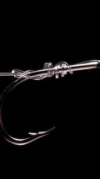 Vertical video. Fishing Hook with Transparent Line and Tightened Knot on Black Background, Macro Close Up with High Contrast Lighting, Slow Motion Secure Connection and Strength Under Tension