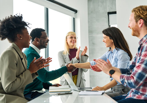 Group of young business people having a meeting shaking hands handshake introducing each other and applauding during meeting in the office. Teamwork and success concept