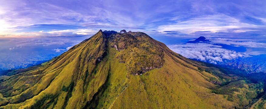 Aerial view of Mount Sumbing featuring rugged slopes and green vegetation under a dramatic sky with clouds Temanggung, Central Java, Indonesia.
