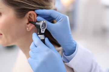 Fototapeta premium Hearing test. Doctor examining woman's ear with otoscope in clinic, closeup