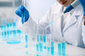 Fototapeta premium Scientist dripping blue liquid into test tube at white table in laboratory, closeup