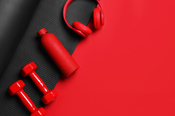 Fototapeta premium Sports equipment, water bottle and headphones on red background, flat lay. Space for text