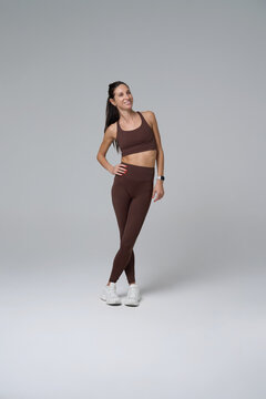 Confident athletic woman posing in full length isolated on grey background