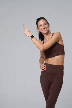 Happy sporty woman pointing up at empty space for text or logo