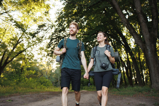 Photo of couple walking in forest at summer with backpacks