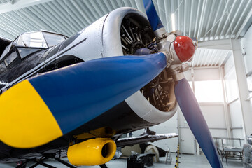 Closeup of vintage aircraft propeller and radial engine inside bright hangar. Blue blades and metallic mechanism create powerful aviation scene with retro engineering and industrial detail © Kyryl Gorlov
