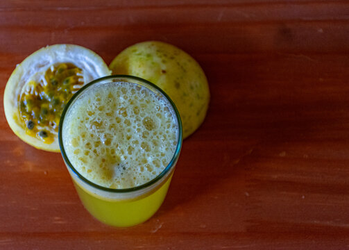 copo com suco de maracuj&aacute; e a fruta ao lado