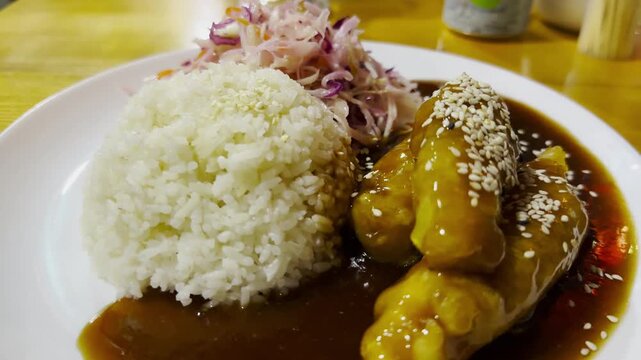 Traditional vietnamese dish arranged on plate at restaurant table. Steamed rice paired with tender chicken and portion of cabbage, creating balanced and inviting composition with clean presentation