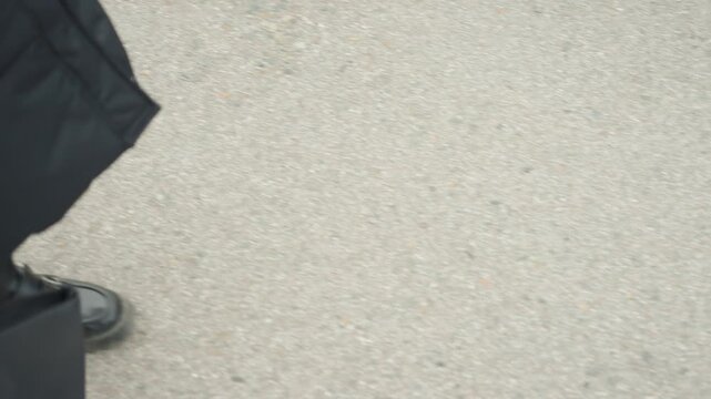 Solitary boot and tote on pavement, closeup of sole and slow shuffle with brief hesitation, tactile asphalt texture and minimal frame, commuter pause with reflective mood, cinematic loopable clip