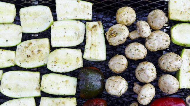 Top view on vegetables roasting on home grill over open heat. Smoke rises gently as meal cook developing lightly charred surface. The focus on grilling process texture and appetizing appearance