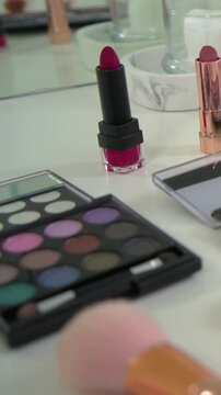 Vertical video: Panning camera over vanity, revealing bright pink lipstick, showcasing palettes