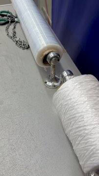 Transparent film white rope on counter showcasing closeup of dispenser with clear stretch film and dense white twine spool ready