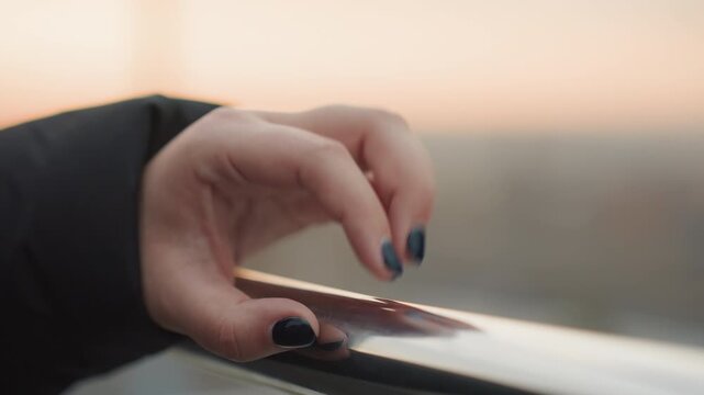 Evening finger dance on rail. Nighttime rhythmic hand movements on metallic fence. Slowpaced cinematic scene showing hand tapping rhythmically on reflective chrome obstacle during twilight