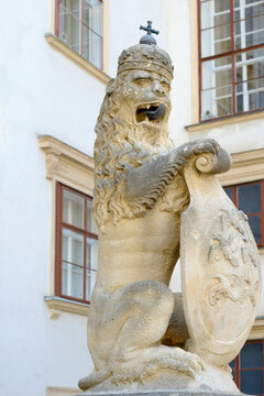 Stone lion statue holding a carved shield 